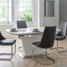 COMO High Gloss White Extendable Dining Table with butterfly extension system, paired with six black quilted chairs in a modern dining room setting.